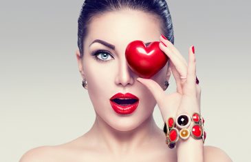 Fashion woman with red heart. Valentine's day art portrait. Beautiful make up and manicure. Surprised model girl face, open mouth, emotion