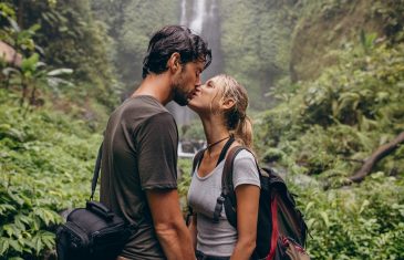 Shot of loving young couple kissing while standing in the forest. Couple in love kissing near a waterfall in forest.