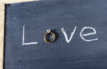The word love spelled out on a chalkboard with a letter replaced with a diamond ring.