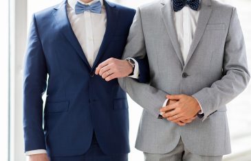 people, homosexuality, same-sex marriage and love concept - close up of happy male gay couple holding hands on wedding
