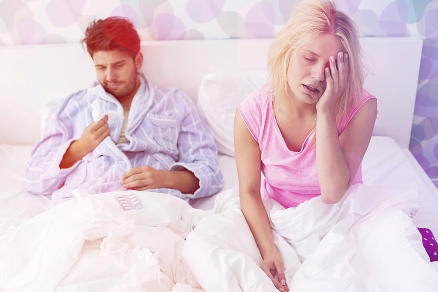 Irritated sick couple on bed at home