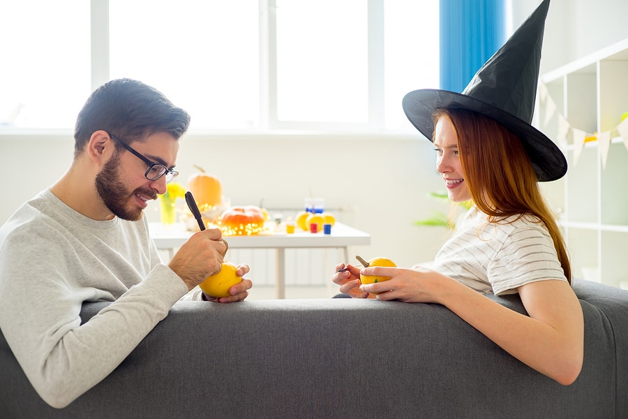 Happy couple playing with halloween pumpkins at home