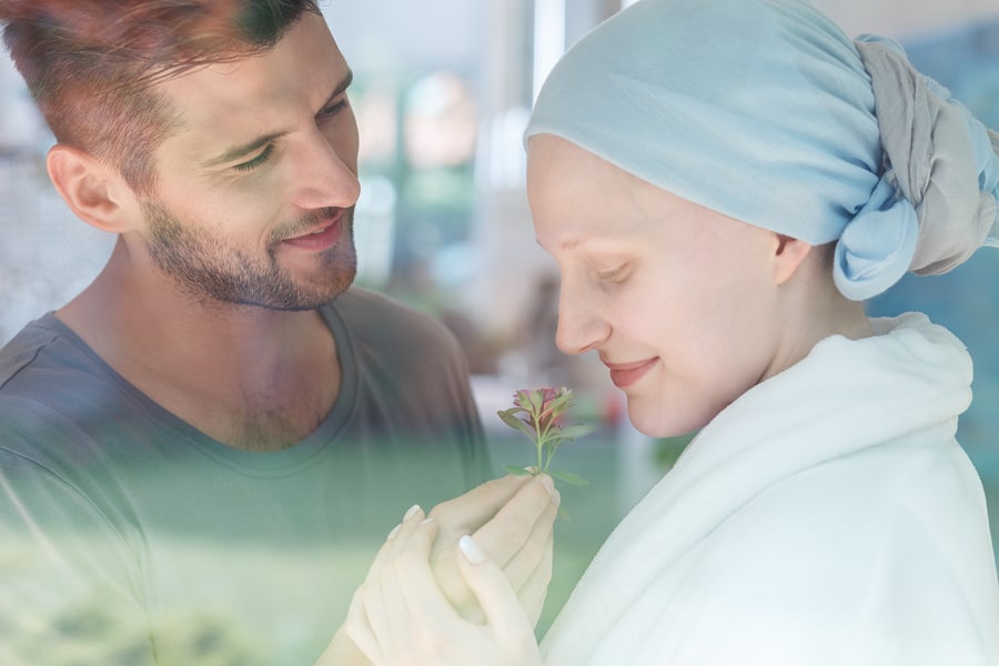 Young sick woman smelling a fresh flower from her husband