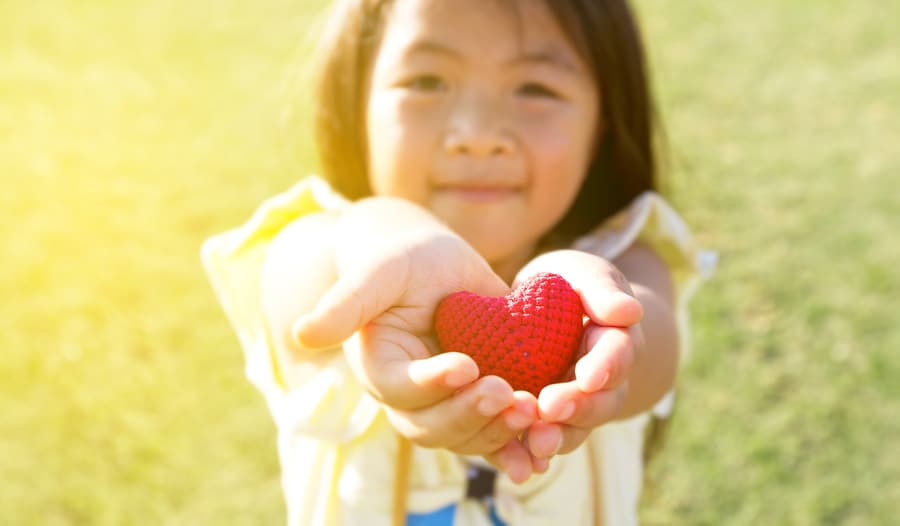 child holding red heart in her hands