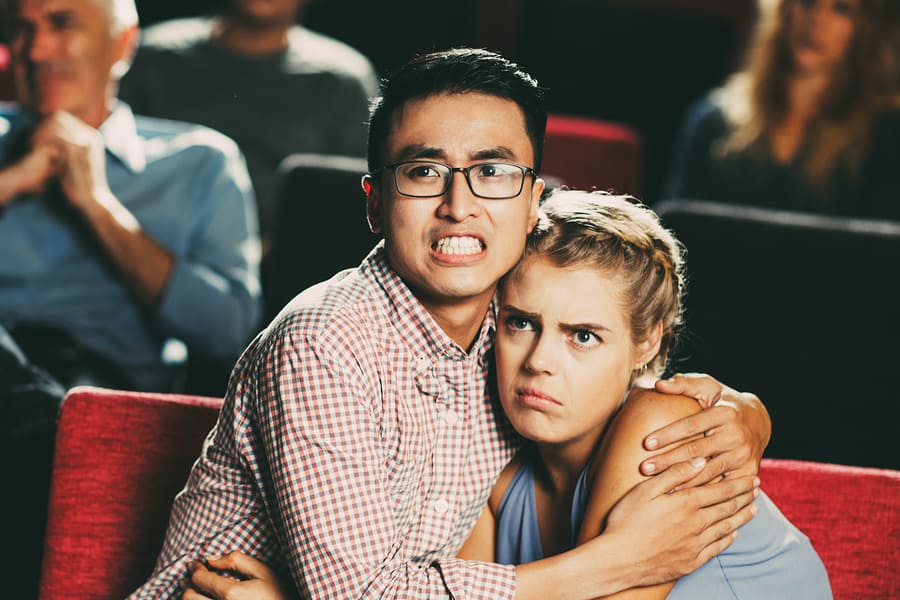 fearful young couple watching scary scene in movie