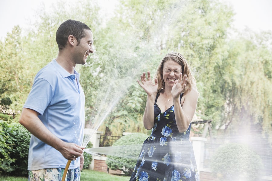 Couple playing with a garden hose and spraying each other
