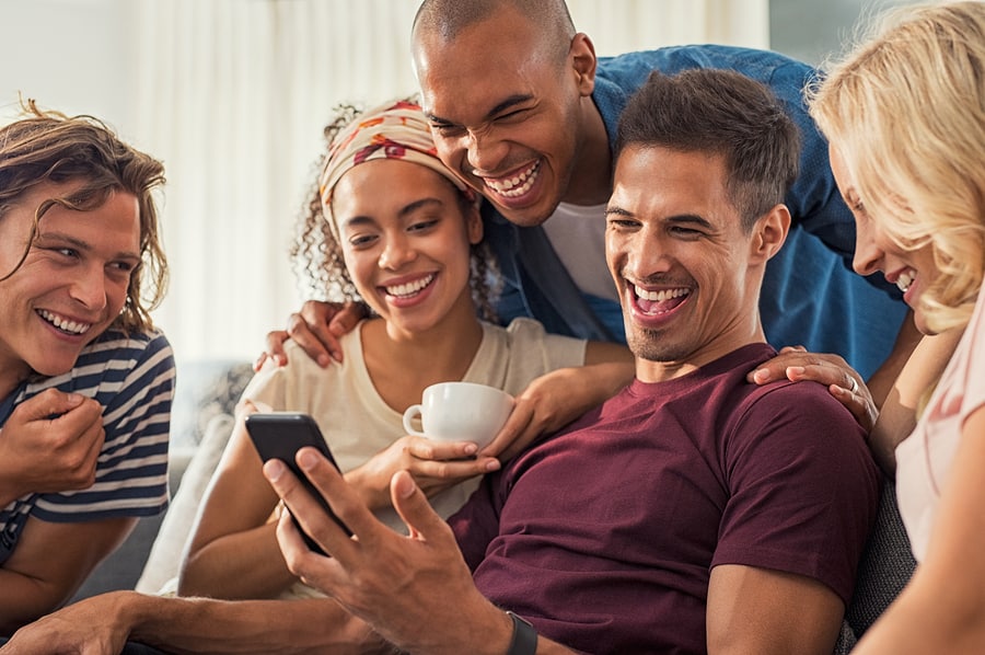 Joyful man showing video on his mobile phone with friends