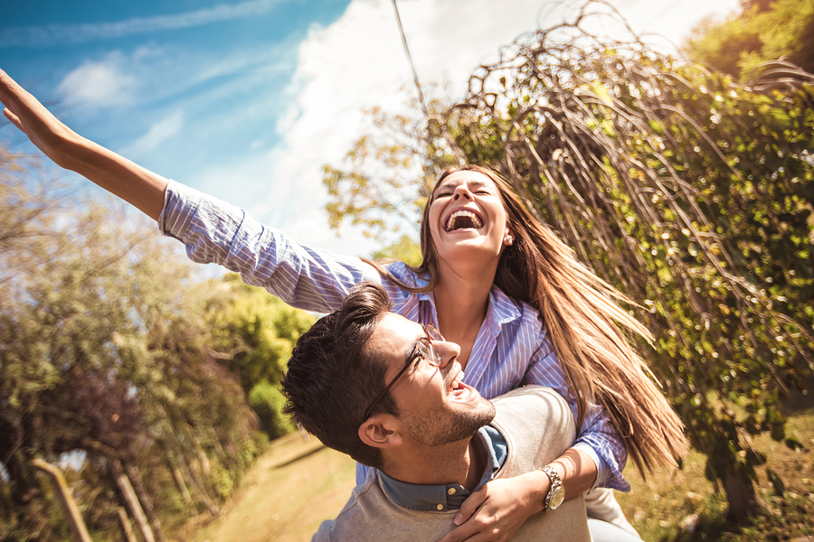 Couple Having Fun Man Giving Piggyback To Woman In Park